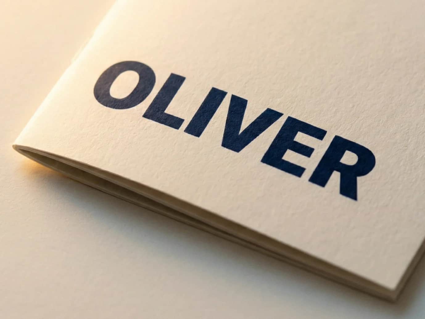 Close-up of a toodaloo personalised colouring book cover showing the name OLIVER printed on premium off-white uncoated stock